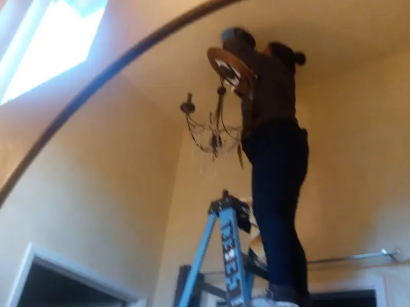 Electrician installing a chandelier in a Mechanicsville residence